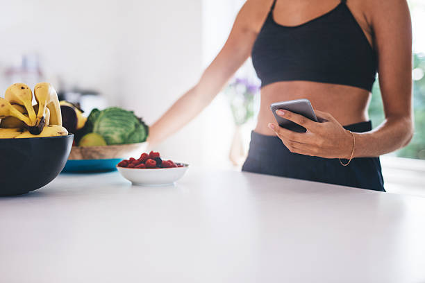istock Young woman with mobile phone in kitchen 637793862