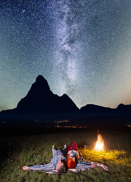 istock Man and woman lying near campfire under beautiful starry sky 637794966