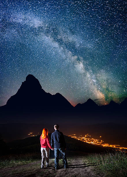 istock Tourists holding hands, standing on hill and enjoying starry sky 637795290