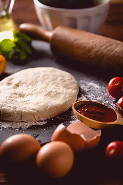 Photo of Dough with flour on wooden table, preparing homemade pizza