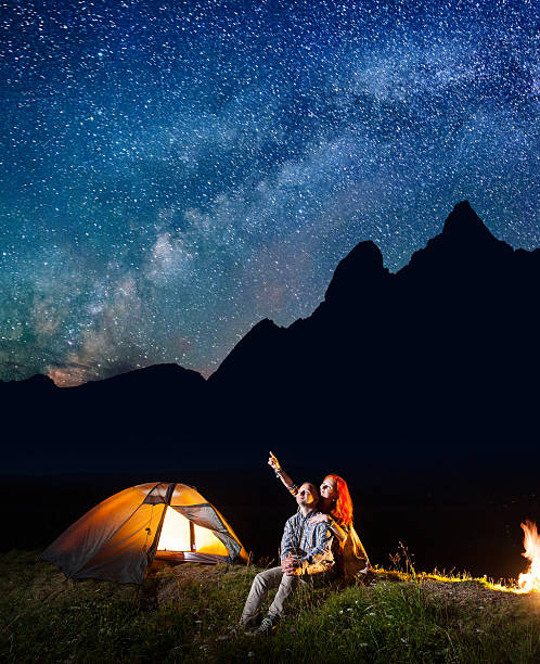 istock Young tourists looking at the shines starry sky at night 637797268