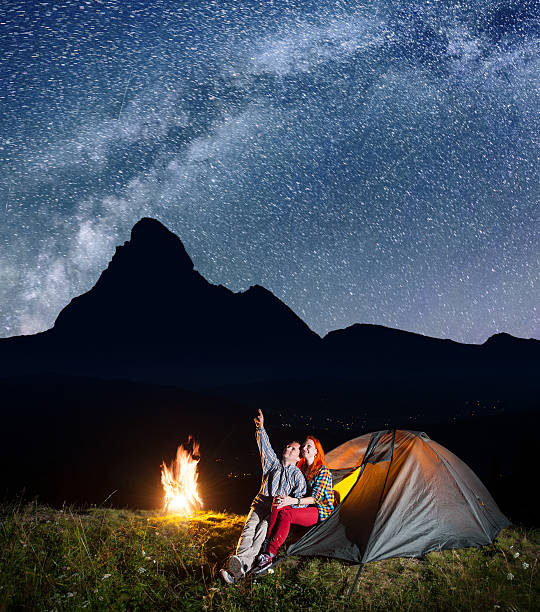 istock Pair of backpackers sitting near tent and fire 637800872