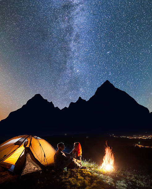 istock Couple hikers sitting in front tent near campfire 637801300