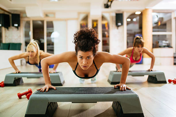 women doing push-ups on step aerobics equipment at gym. - the next step imagens e fotografias de stock