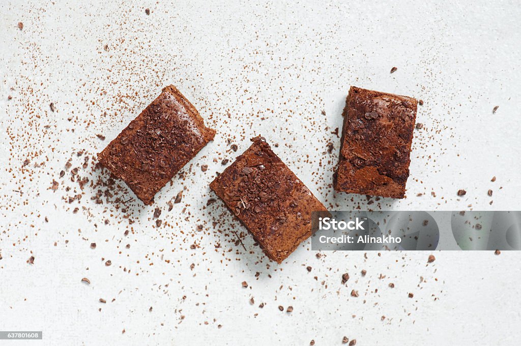 Three pieces of brownie topped with chocolate chips and cocoa Three pieces of brownie topped with chocolate chips and cocoa on the light table Brownie Stock Photo