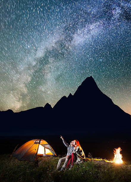 istock Pair sitting near the shining tent and campfire 637803560