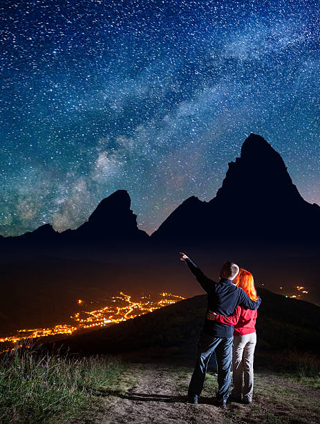 istock Romantic man shows on stars in starry sky at night 637804342