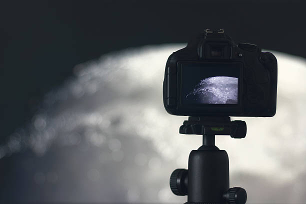 Moon photography. Camera with tripod capturing moon.