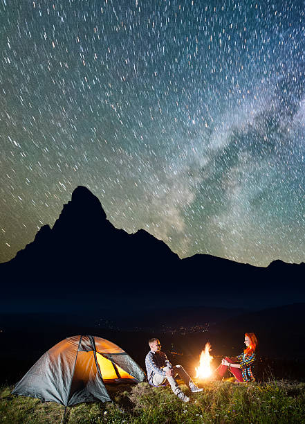istock Tourist family sitting by bonfire under incredibly beautiful starry sky 637804792