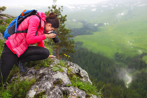 istock Woman with camera making photo on mountain peak 637804984