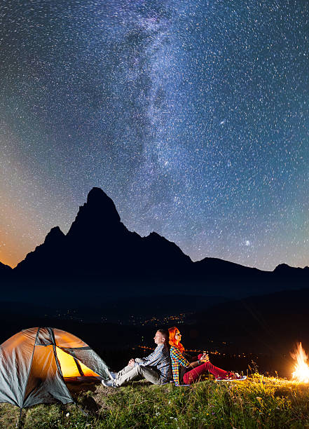 istock Girl and guy sitting by campfire near tent 637807796