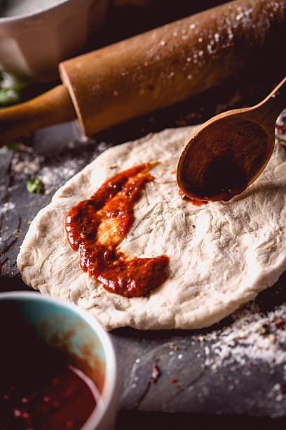 istock Girl is placing tomato sauce on fresh pizza 637808362
