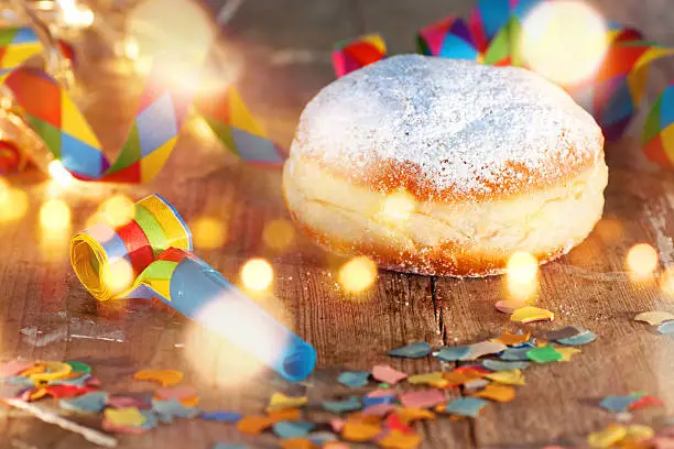 Delicious donuts on a wooden table with confetti and bokeh for carnival and party