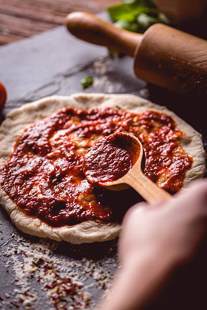 istock Girl is placing tomato sauce on fresh pizza 637808934