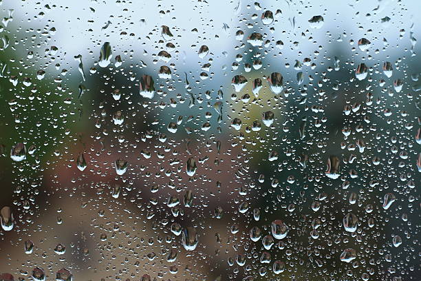 istock Rain drops on window with house and church in background 637810166