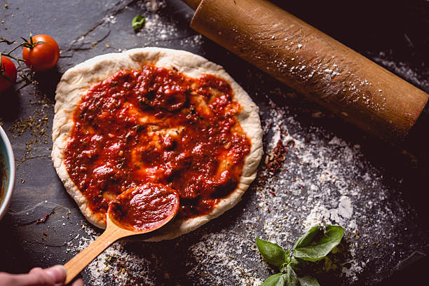 istock Girl is placing tomato sauce on fresh pizza 637811476