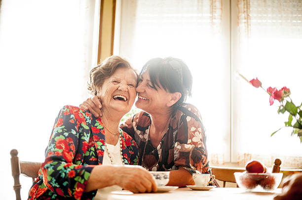 femme âgée se détendre avec sa fille à la maison - friendship coffee home interior women photos et images de collection