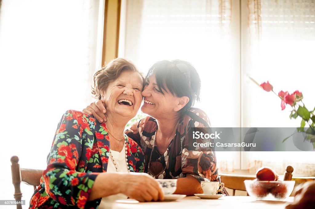 Senior Woman Relaxing with her Daughter at Home Senior Woman Enjoying a relaxing moment with her Daughter at Home drinking Coffee Senior Adult Stock Photo