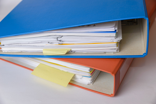 A orange and a blue binder isolated with documents.