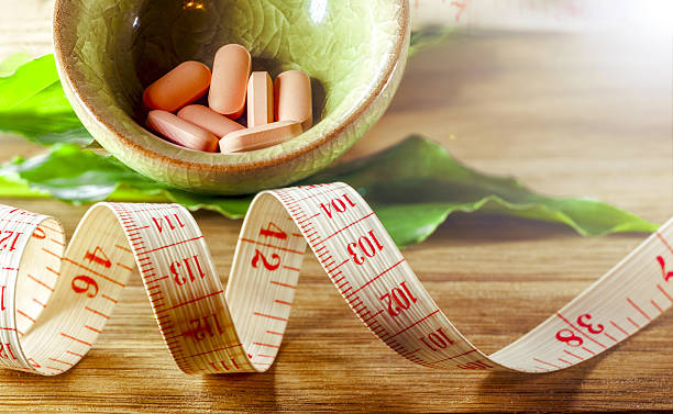 диетические таблетки соперничают сантиметр. понятие диеты, здоровья - vitamin pill excess pill capsule стоковые фото и изображения