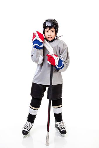 Junior ice hockey player with full equipment and uniform isolated on white background.