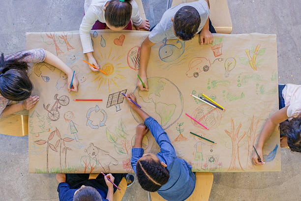 Environmentally Friendly Art An aerial view of a multi ethnic group of children learn about going green and color in environmentally friendly concepts surrounding a drawing of Earth. creativity in kids stock pictures, royalty-free photos & images