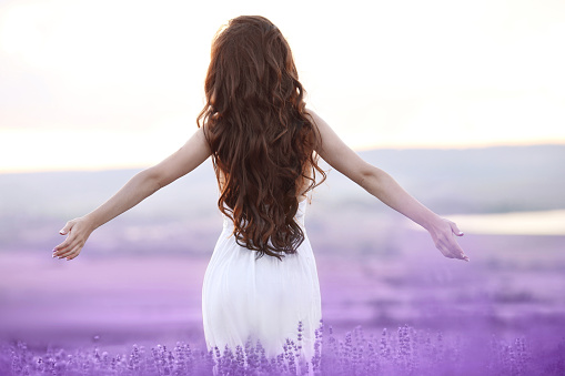 Free brunette woman with open arms enjoing sunset in lavender