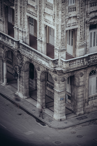 Havana, Cuba - October 10, 2016: Birds eye view of corner building on Prado boulevard in Old Havana. This is one of major routes in the centre of the city, leading from sea shore to Capitolio (Cuban Parliament building). Facade on the corner with colonial style architecture. People on the sidewalk. Evening hours in the Havana.