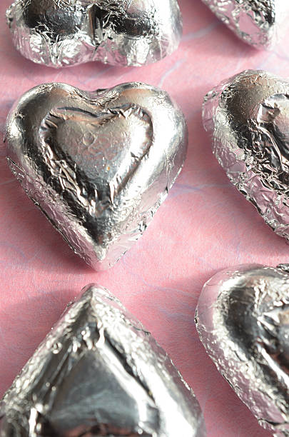 istock chocolate heart candy wrapped in silver foil on pink paper 637837154