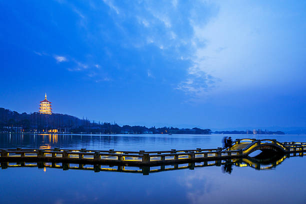 ancient pedestian bridge on water at twilight landmark architecture called Leifeng Tower near West Lake in Hangzhou at twilight west lake stock pictures, royalty-free photos & images