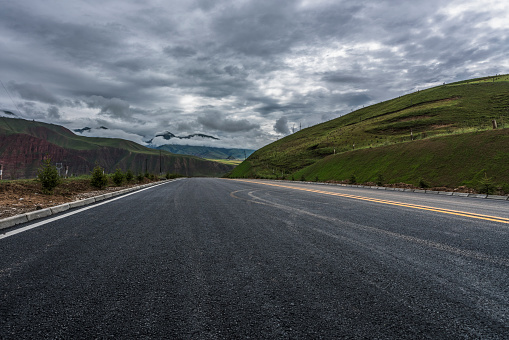 empty asphalt road to horizon under cloudy sky.