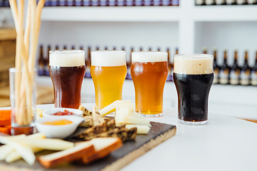 Close-up of four glasses of different craft beer with snack board