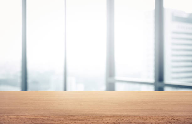 istock Wood table with blur room office and window city view 637864586