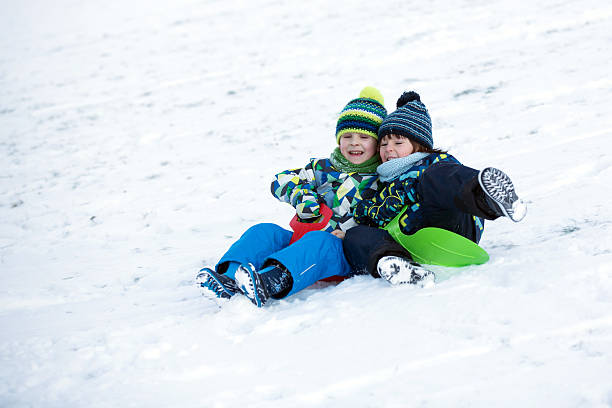 istock Two kids, boy brothers, sliding with bob in the snow 637865092