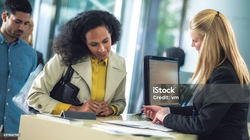 Bank teller explaining loan details to customer Two women, a customer and employee, discussing loan terms at a bank counter. Bank Teller Stock Photo