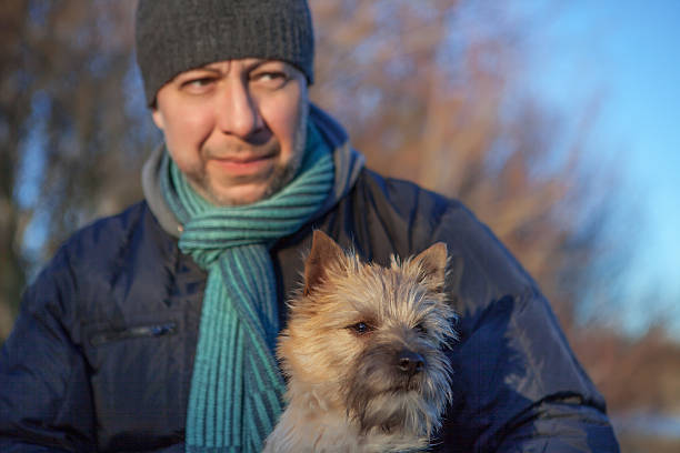 istock Man with a puppy Cairn Terrier on the lake 637867156