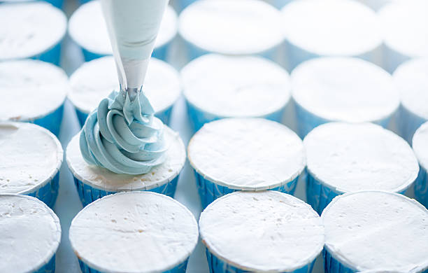 Squeeze the cream filling on the blue cupcake, soft focus