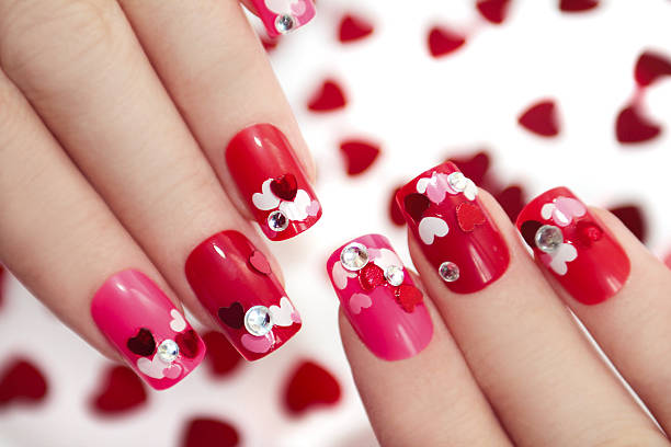 Nail designs with hearts. Nail designs with different sequins in the shape of hearts on red and pink nails for girls. red nail polish stock pictures, royalty-free photos & images