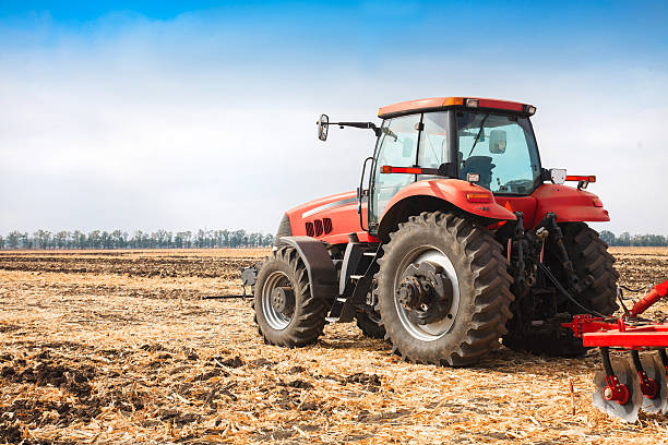 Tractor rojo en el campo en un día soleado y brillante. - foto de stock