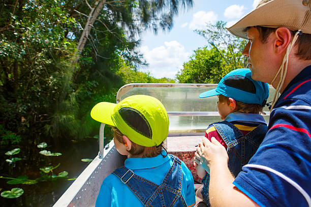 Two little kids boys and father making Everglades boat tour Two little kids boys and father making air boat tour in Florida wetland swamp at Everglades National Park in USA. Family, dad and children discovering wild nature and animals. Family having fun. everglades national park photos stock pictures, royalty-free photos & images