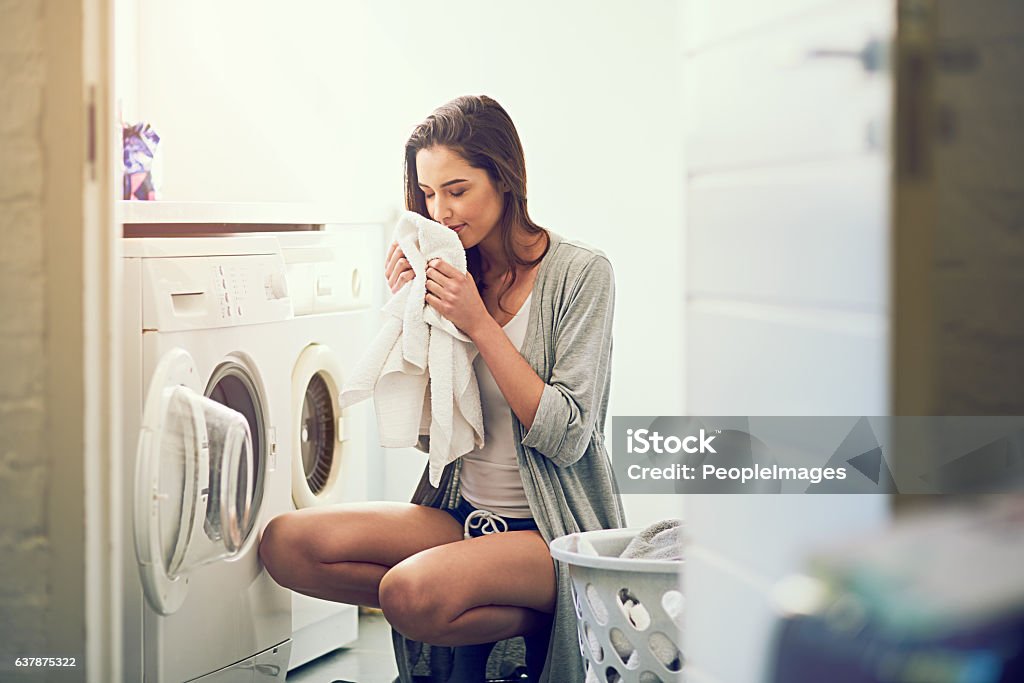 I love the smell of cleanliness Cropped shot of a young woman smelling her freshly washed towels Laundry Stock Photo