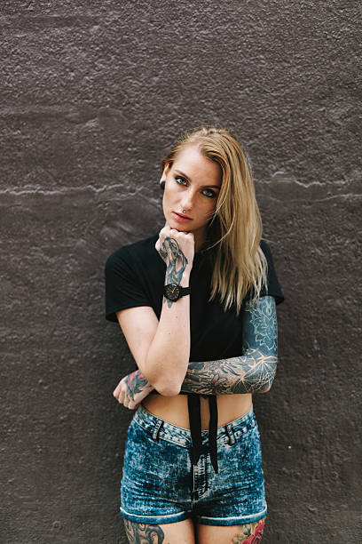 istock Tattooed Woman Leaning on a Dark Wall 637878164