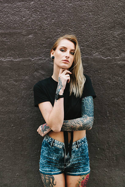 istock Tattooed Woman Leaning on a Dark Wall 637878238