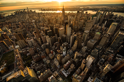 Helicopter point of view of New York City skyscrapers at sunset. Empire State building and many details are visible in the image.