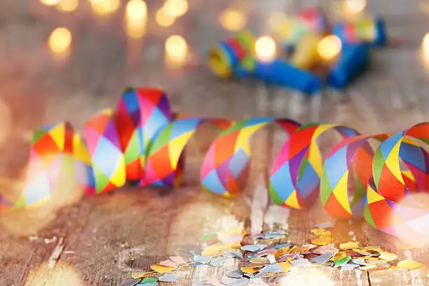 Colorful confetti and air streamer on rustic wooden table with bokeh