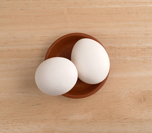 istock Two eggs in a small bowl atop a wood table. 637883524