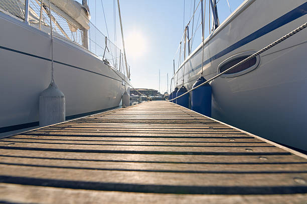 Marina with anchored boats Perspective of small floating pier on still water marina stock pictures, royalty-free photos & images