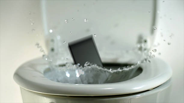 Phone landing in a toilet bowl. stock photo