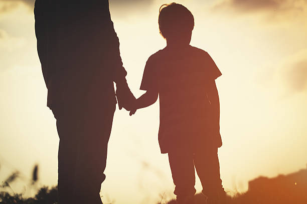 istock silhouette of father and son holding hands at sunset 637888148