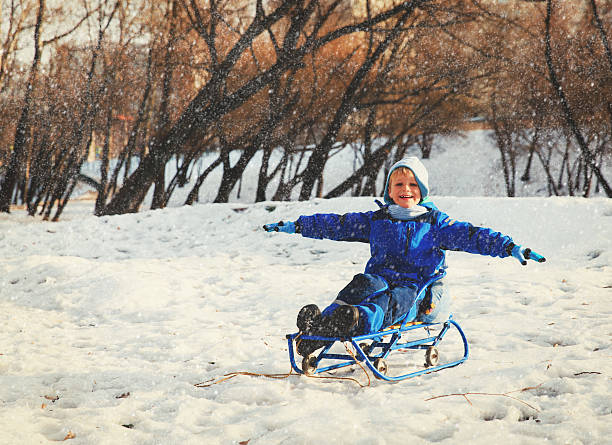 istock happy little boy on sledge in winter snow 637888934
